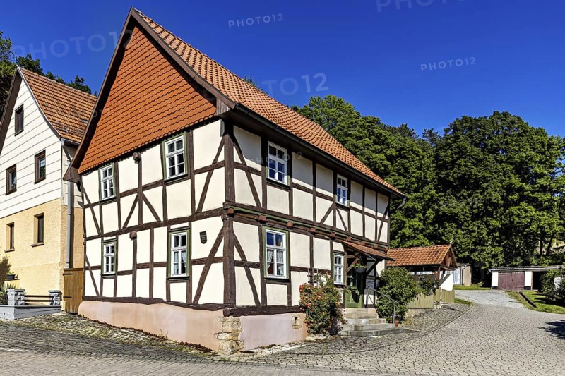 A picturesque half-timbered house with red roof tiles under a bright blue sky in the countryside, Historic half-timbered houses in the town of Treffurt in Thuringia