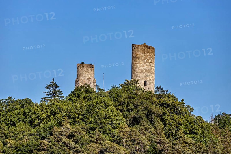 Close-up of two castle towers, embedded in dense green vegetation against a clear blue sky, The Brandenburg ruins in the Werra valley near Lauchröden in Thuringia