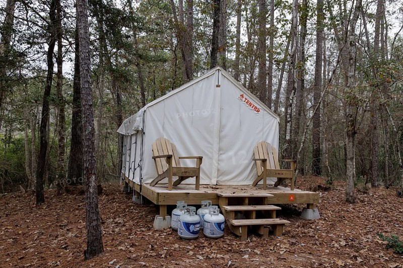 Propane tanks outside a Tentrr glamping tent on a raised platform with a wooden porch at Clarko State Park near Quitman, Mississippi, USA