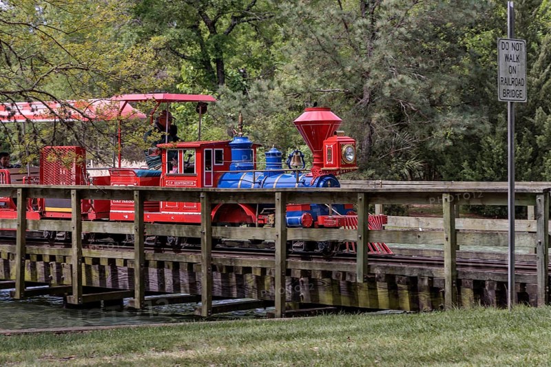 Hermann Park Railroad train, a one-third size replica of an 1863 C.P. Huntington steam train crosses a bridge over a part of McGovern Lake in Hermann Park in downtown Houston, Texas
