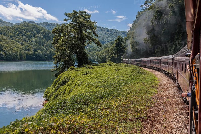 Steam from the Great Smoky Mountains Railroad hangs in the air as the train rounds a curve through the mountains of North Carolina