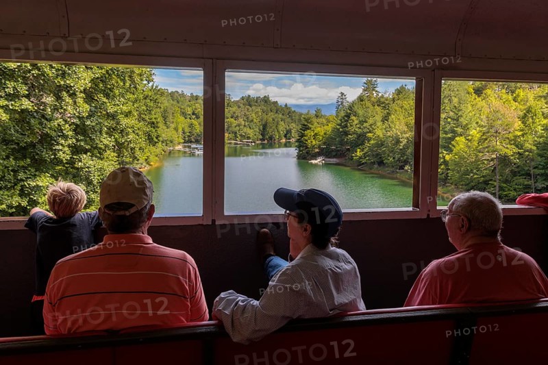 Great Smoky Mountains Railroad passengers looking out the windows of the open air train car while on an excursion from Bryson City, North Carolina