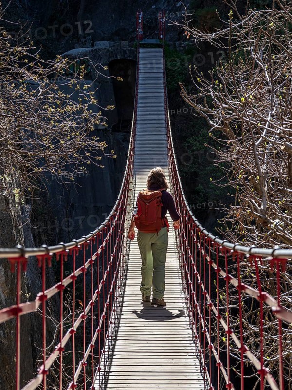 Woman on suspension bridge, hiking path Los Cahorros de Monachil, along the Rio Monachil river, narrow path in the river gorge, Monachil near Granada, Andalusia, Spain