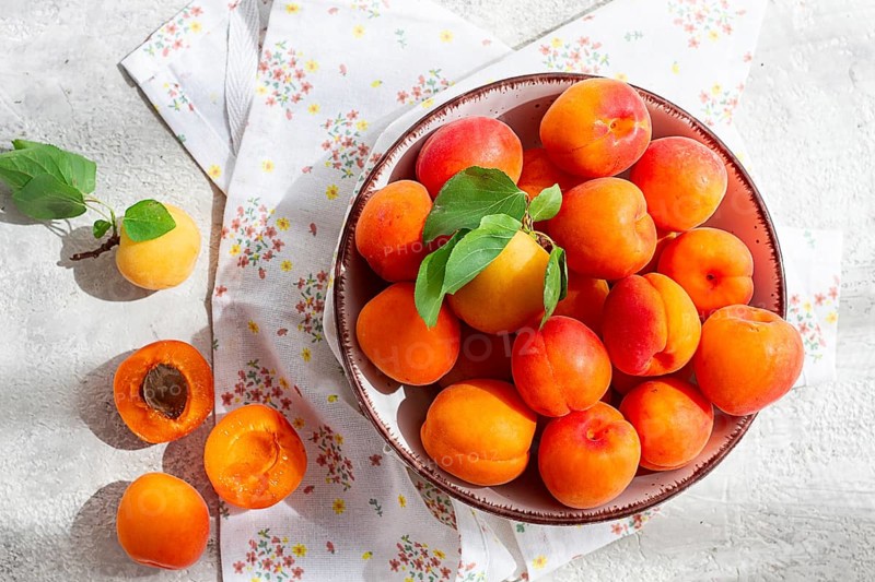 Fresh apricots in a bowl, on a bright table, natural light, top view, no people