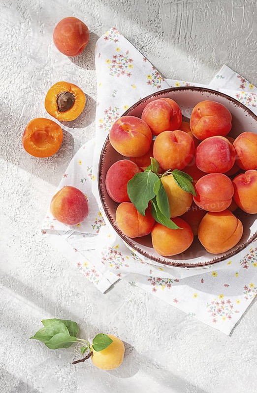 Fresh apricots in a bowl, on a bright table, natural light, top view, no people