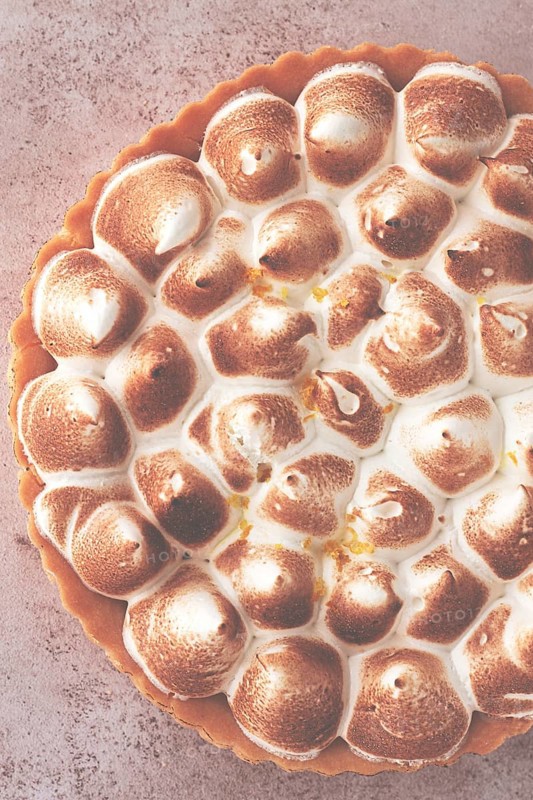 Lemon meringue cake, golden brown, toasted, on a light table, no people