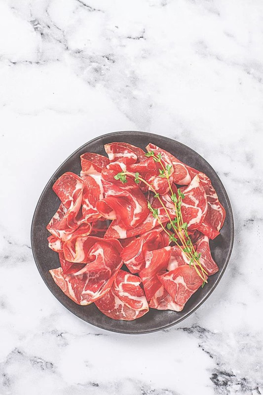 Plate with sliced cured meat, pork neck, prosciutto coppa, Italian delicacy