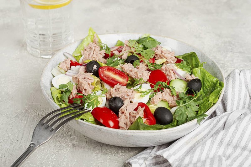 Salad with canned tuna, vegetable salad with quail eggs, lettuce and romaine leaves, red onion, cherry tomatoes, olives, keto food, healthy eating
