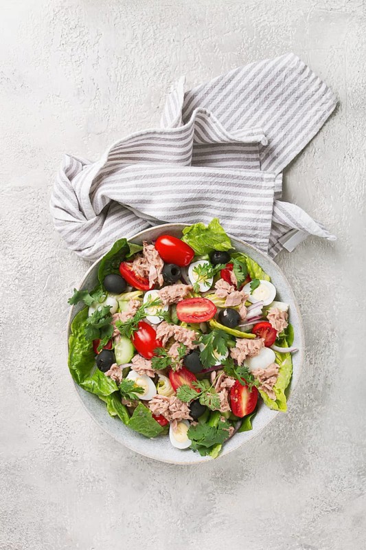 Salad with canned tuna, vegetable salad with quail eggs, lettuce and romaine leaves, red onion, cherry tomatoes, olives, keto food, healthy eating