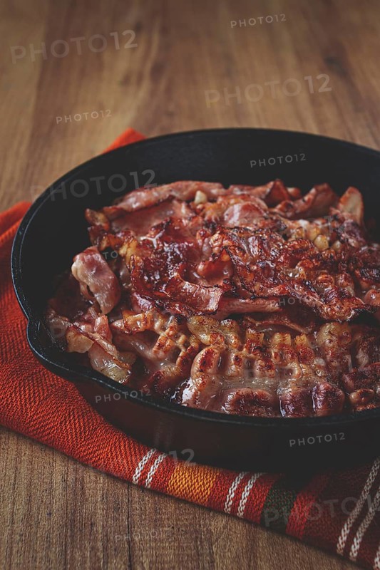 Crispy bacon, on a cast-iron skillet, on a wooden table, rustic style, no people