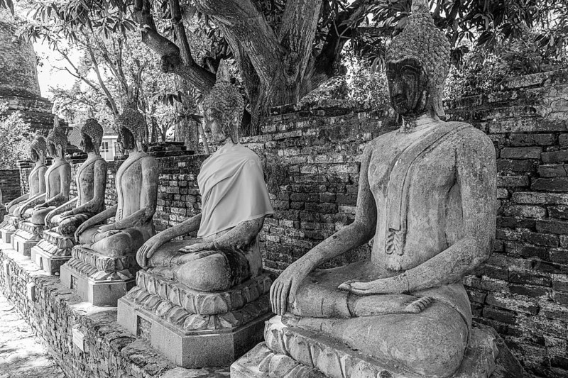 Stone Buddha statues sitting in a row, historic Buddhist temple complex, black and white photo, Ayutthaya, Thailand