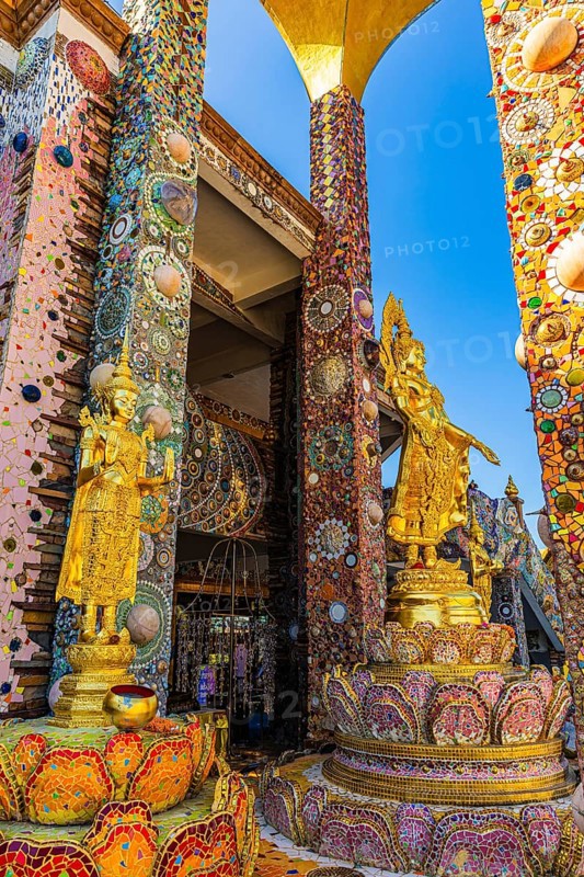 Gilded Buddha statues standing on pedestals decorated with mosaics and glass works of art, Buddhist temple complex Wat Phra That Sorn Kaew, Phetchabun province, Thailand