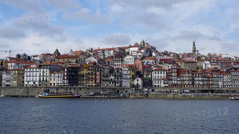 Panoramic view of the Douro in Porto with colorful buildings on the river under cloudy sky, Porto, Portugal