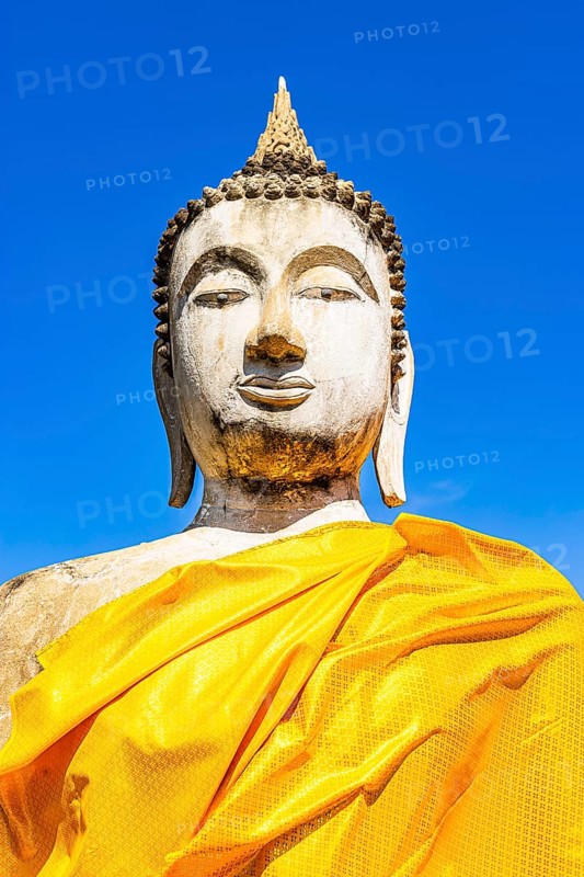 Stone Buddha statue decorated with yellow cloths, historic Buddhist temple complex, Ayutthaya, Thailand