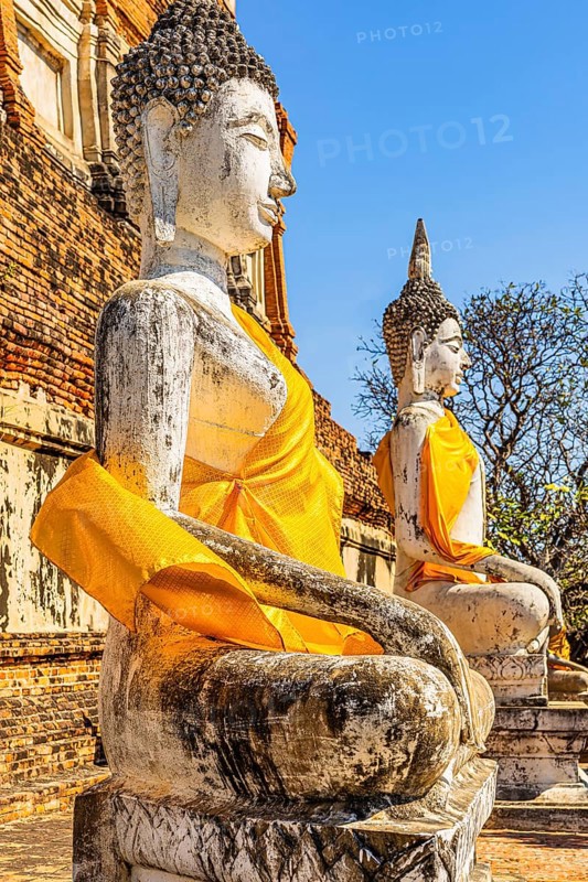 Stone Buddha statues decorated with yellow cloths, historic Buddhist temple complex, Ayutthaya, Thailand
