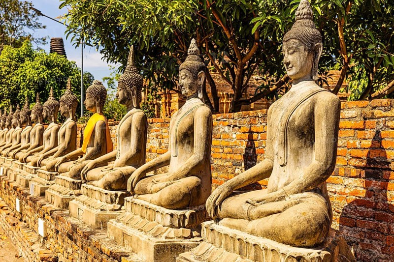 Stone Buddha statues sitting in a row, historic Buddhist temple complex, Ayutthaya, Thailand