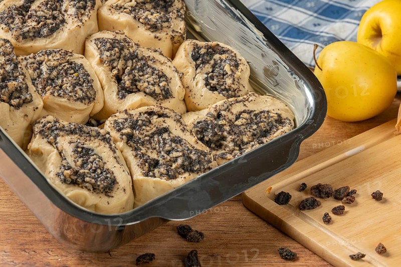 Dough pieces with poppy and apple filling in a baking pan ready for baking