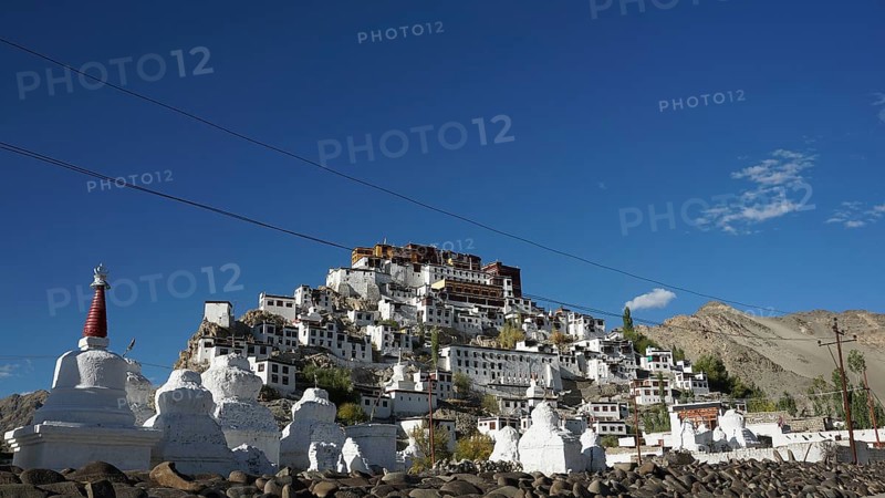 The sprawling Thiksey Buddhist monastery with several stupas against a mountain backdrop under a blue sky, trekking in Ladakh, Himalayas, India