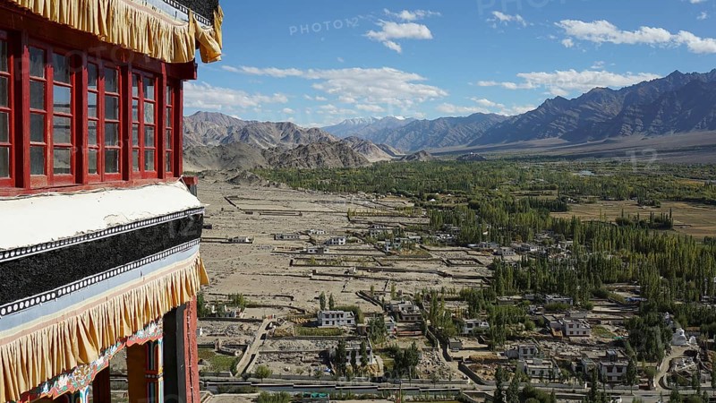 View from a Buddhist monastery of a settlement and vast mountain landscape under blue sky, trekking in Ladakh, Himalayas, India