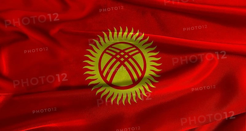 Flag of Kyrgyzstan with fabric textured background. Close up of National flag of Kyrgyzstan with realistic texture