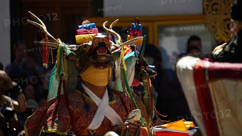 Person wearing painted animal mask with antlers and traditional garments in festive ceremony in Leh, trekking in Ladakh, Himalayas, India