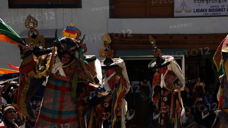 Several masked figures in colorful clothes perform a dance during a festival in Leh, trekking in Ladakh, Himalayas, India
