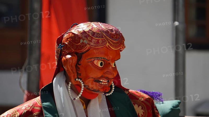 A vivid red-orange masked figure at a Buddhist ritual or dance in Leh, trekking in Ladakh, Himalayas, India