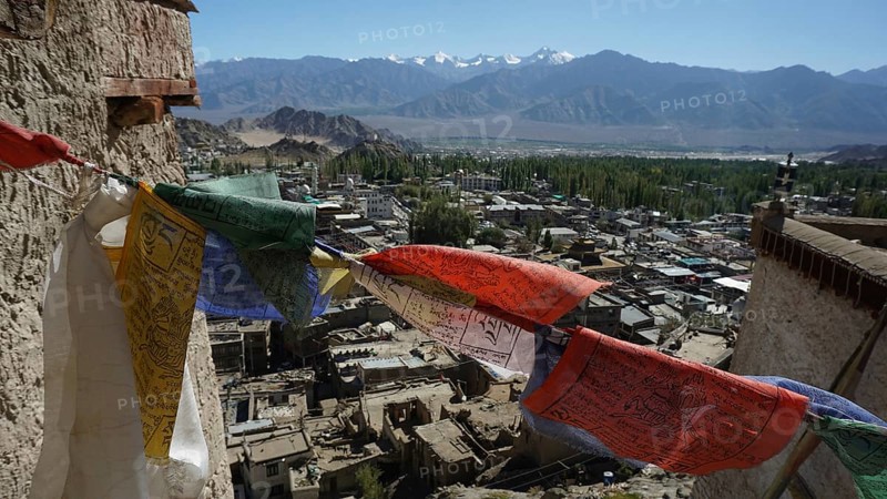 Colorful prayer flags fly over Leh with a mountainous landscape in the background, trekking in Ladakh, Himalayas, India