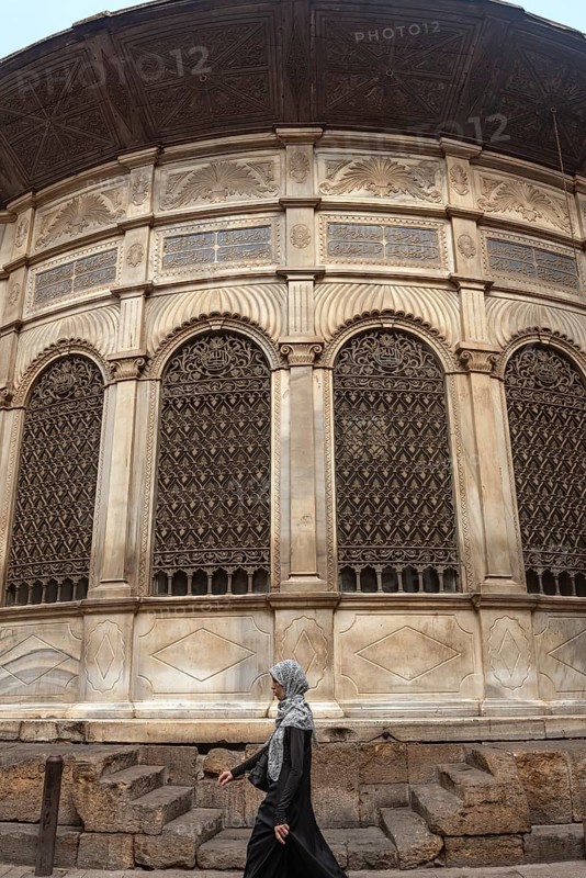 Cairo, Egypt. July 7th 2024 A local woman walks past one of the many restored monuments along Sharia Al Muizz Li Din Allah near Khan El Khalili Bazaar, historical Cairo, Egypt