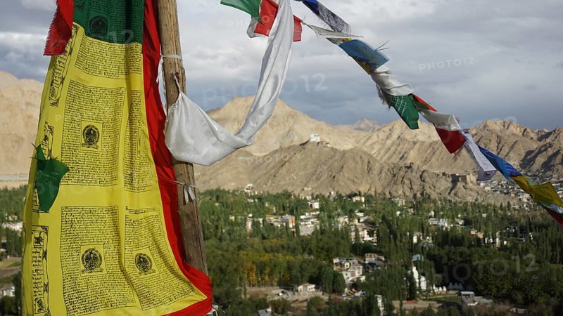 Close-up, colorful prayer flags fluttering in the wind against a mountainous landscape with clear sky, Leh, trekking in Ladakh, Himalayas, India