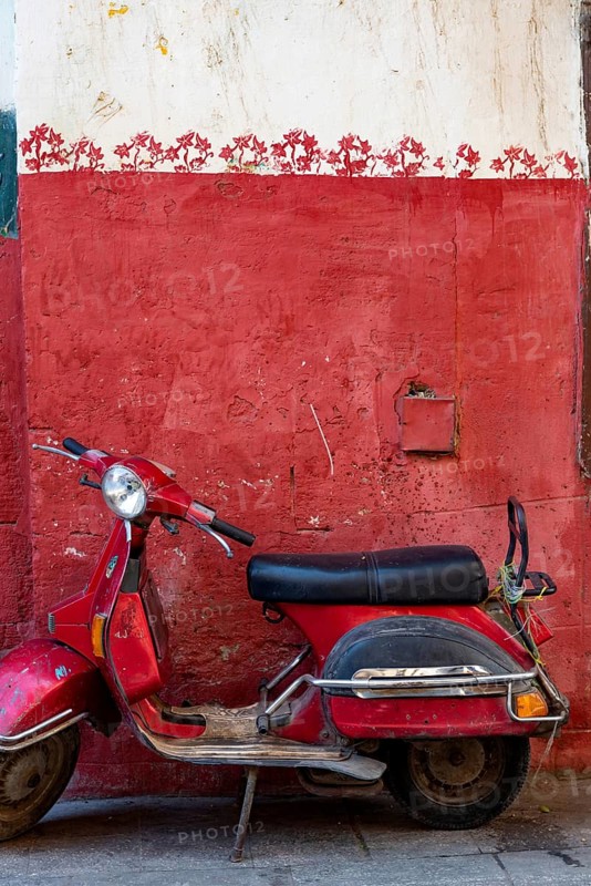Cairo, Egypt. November 26th 2022 Cute red motor scooter parked against a red painted wall in the Islamic quarter of Cairo near the Khan el Khalili Bazaar, Egypt