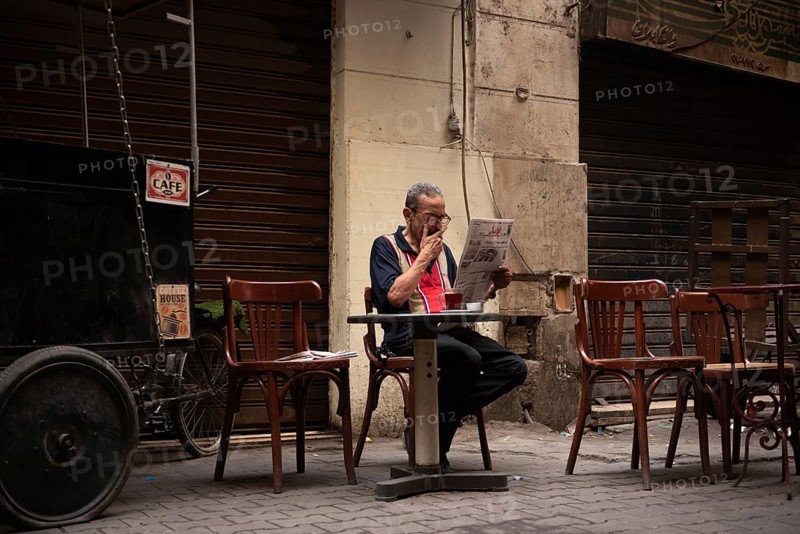 Cairo, Egypt. June 14th 2024 An Egyptian man smokes, drinks tea and reads a newspaper in local café in Downtown Cairo, Egypt