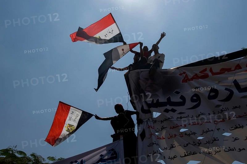 Cairo, Egypt. July 15th 2011 Anti government protestors with banners and flags silhouetted against the sky, Tahrir square, Cairo, Egypt. A young Egyptian girl shows the victory sign during a protest in Tahrir Square after the Egyptian revolution on January 25th