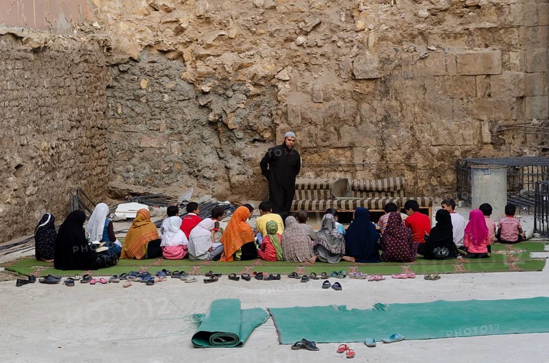 Cairo, Egypt. 21st October 2011 An open air school class and Muslim teacher giving lessons to children sitting on the floor in the poor Al Darb al Ahmar neihborhood of Islamic Cairo