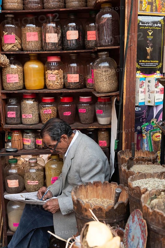 Cairo, Egypt. December 7th 2022 An Egyptian man doing a crossword while sitting in a spice shop in the Khan El Khalili Bazaar, a popular tourist market in the Islamic Quarter of Cairo, Egypt