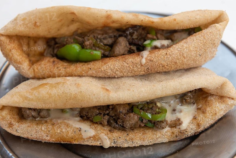 A plate of tasty fried liver and spicy green pepper sandwiches, one of the most popular street food snacks in Egypt being prepared at a Cairo street stall