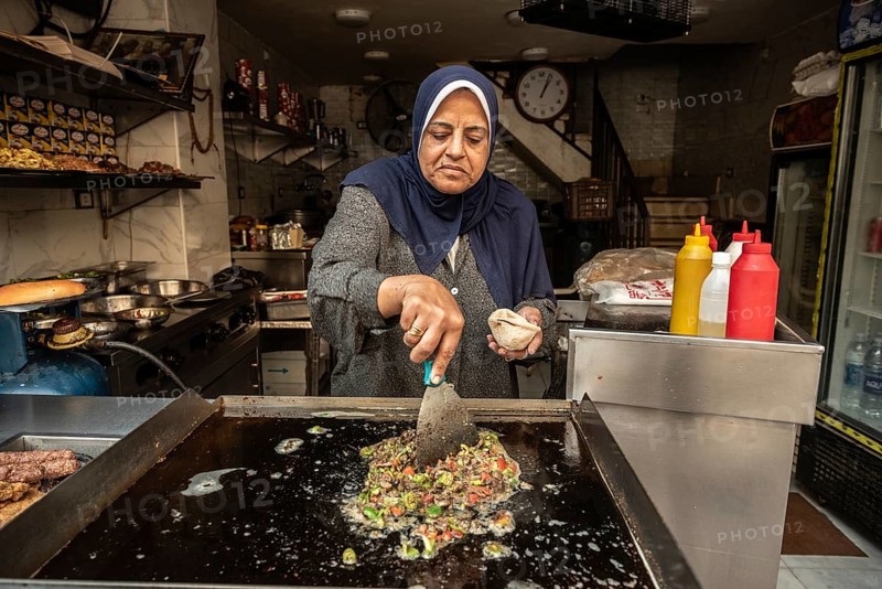 Cairo, Egypt. November 30th 2022 An Egyptian woman frying hot green peppers and chopped liver to make liver sandwiches a popular Egyptian street food snack, Cairo, Egypt