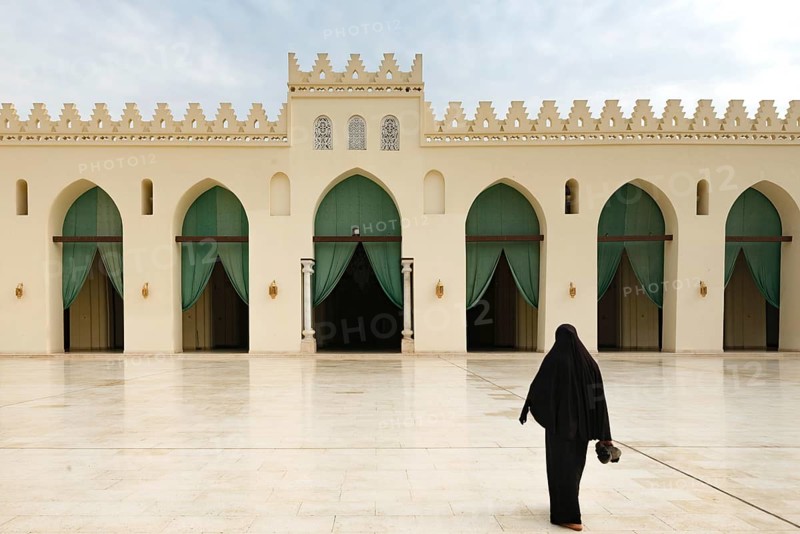 A Muslim women entering the prayer hall of historic Mosque of al-Hakim, also known as Al-Anwar, named after Al-Hakim bi-Amr Allah. Just inside the Fatimid gate, Bab al-Futuh in Islamic Cairo, Egypt