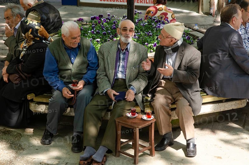 Bursa, Turkey. April 21st 2014 Old Turkish men chatting and drinking tea in a tree shaded square, Bursa City, Turkey