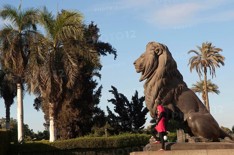 Cairo, Egypt. December 10th 2009 Young Egyptian Muslim women poses for photographs beside a statue of a lion, downtown Cairo, Egypt