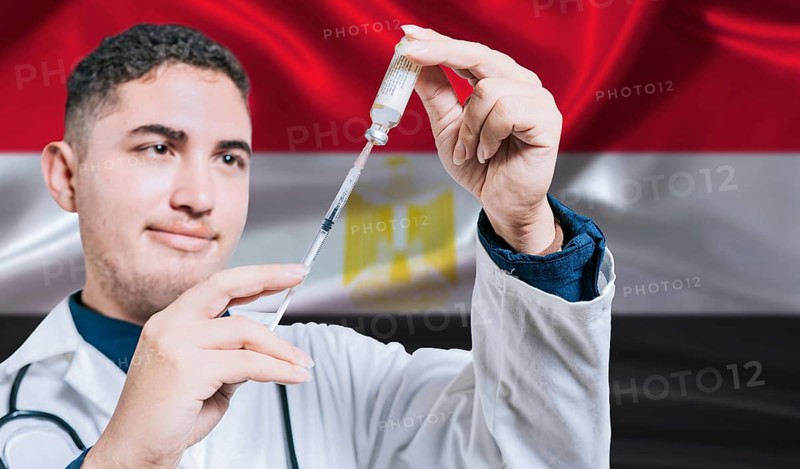 Doctor holding syringe on Egypt flag background. Medical professional holding syringe with Egyptian flag in the background