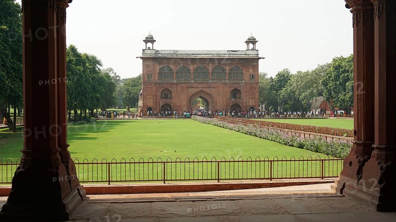 Historic gate with green lawn and trees, Red Fort in Delhi with numerous visitors in the area, Delhi, India