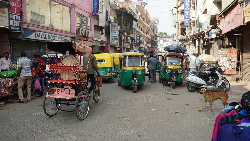Busy shopping street with rickshaws and people in the bustling Indian city of Delhi, India