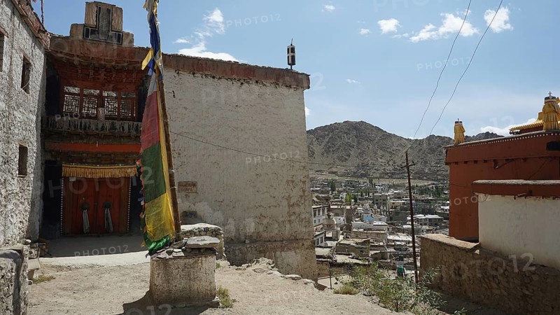 Houses and a colorful big prayer flag with mountains in the background under blue sky, Leh, city view from Leh Palace over Leh with mountains and cloudy sky, Ladakh, North India, Himalayas, India