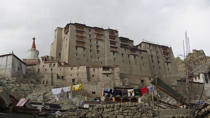 Large fortress complex, Leh Palace with hanging laundry, against cloudy sky, Ladakh, North India, Himalayas, India