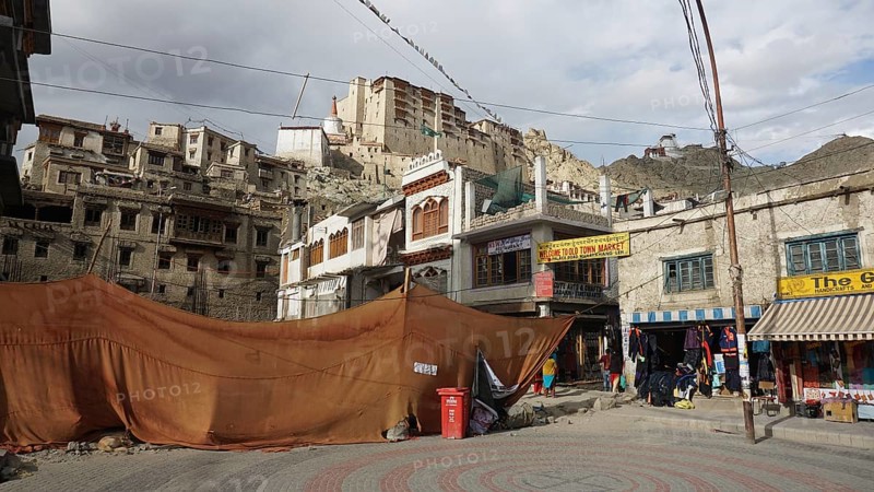 Leh Palace and historic buildings with market stalls and tents against a mountainous backdrop in Leh, Ladakh, North India, Himalayas, India