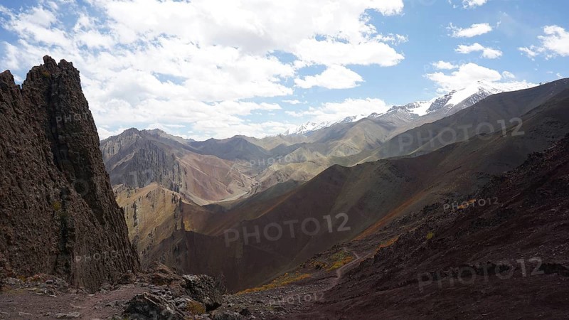 Wide mountain landscape with snowy peaks under cloudy sky, trekking at Stok La Pass in Ladakh, Himalayas, India