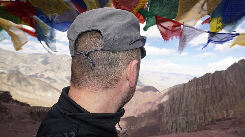 Person looking at a vast mountain landscape under fluttering prayer flags, trekking at Stok La Pass in Ladakh, Himalayas, India