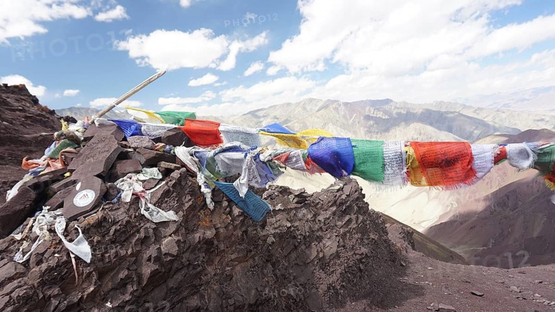 Colourful prayer flags flying over a rocky mountain landscape, trekking at Stok La Pass in Ladakh, Himalayas, India