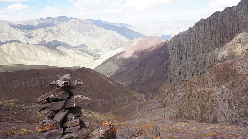 Stone tower as a guide with a view of extensive, rocky mountain landscape, trekking at Stok La Pass in Ladakh, Himalayas, India